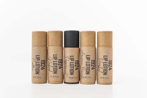 Five lip lotion bottles with brown and black labels on a white background