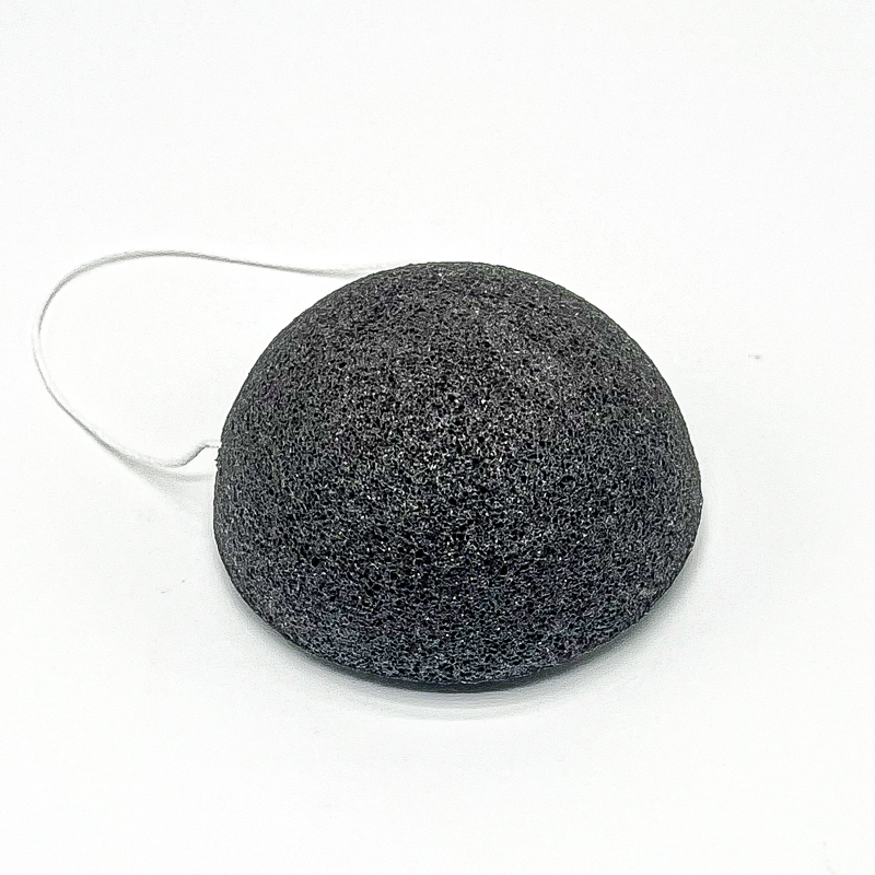 Black facial sponge with a string on a white background