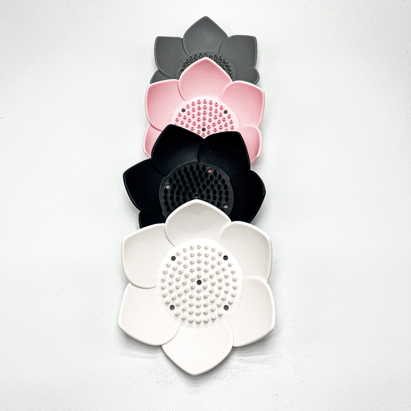 Set of four flower-shaped strainers in white, black, pink, and gray on a white background
